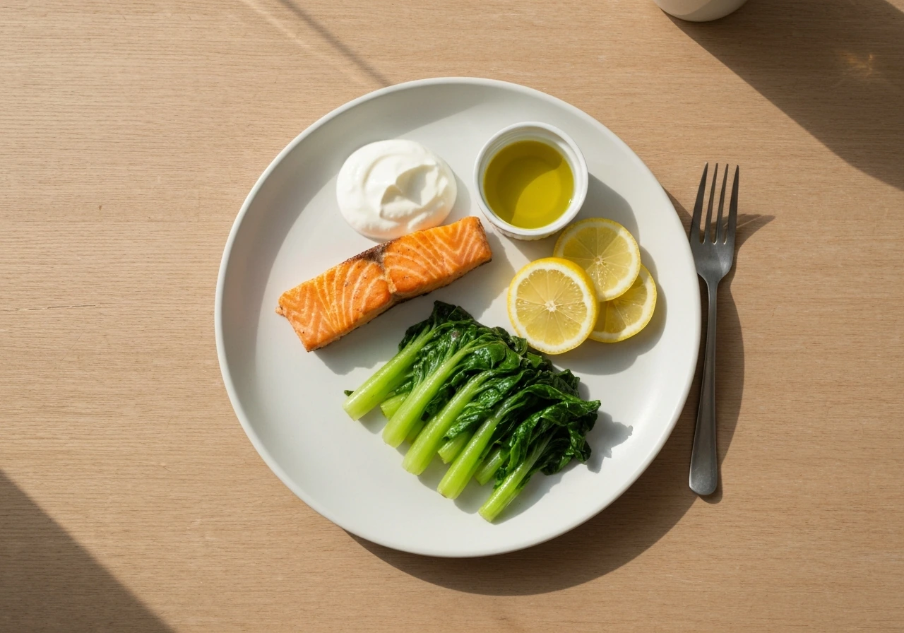 A simple plate of salmon, Greek yogurt, and greens arranged to suggest protein and calcium/vitamin D nutrition.